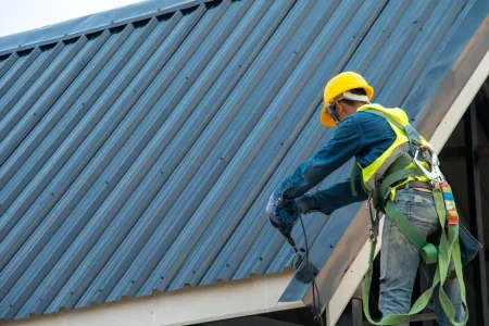 metal-roof-installation-man-in-safety-gear-installing-corrugated-metal-roofing